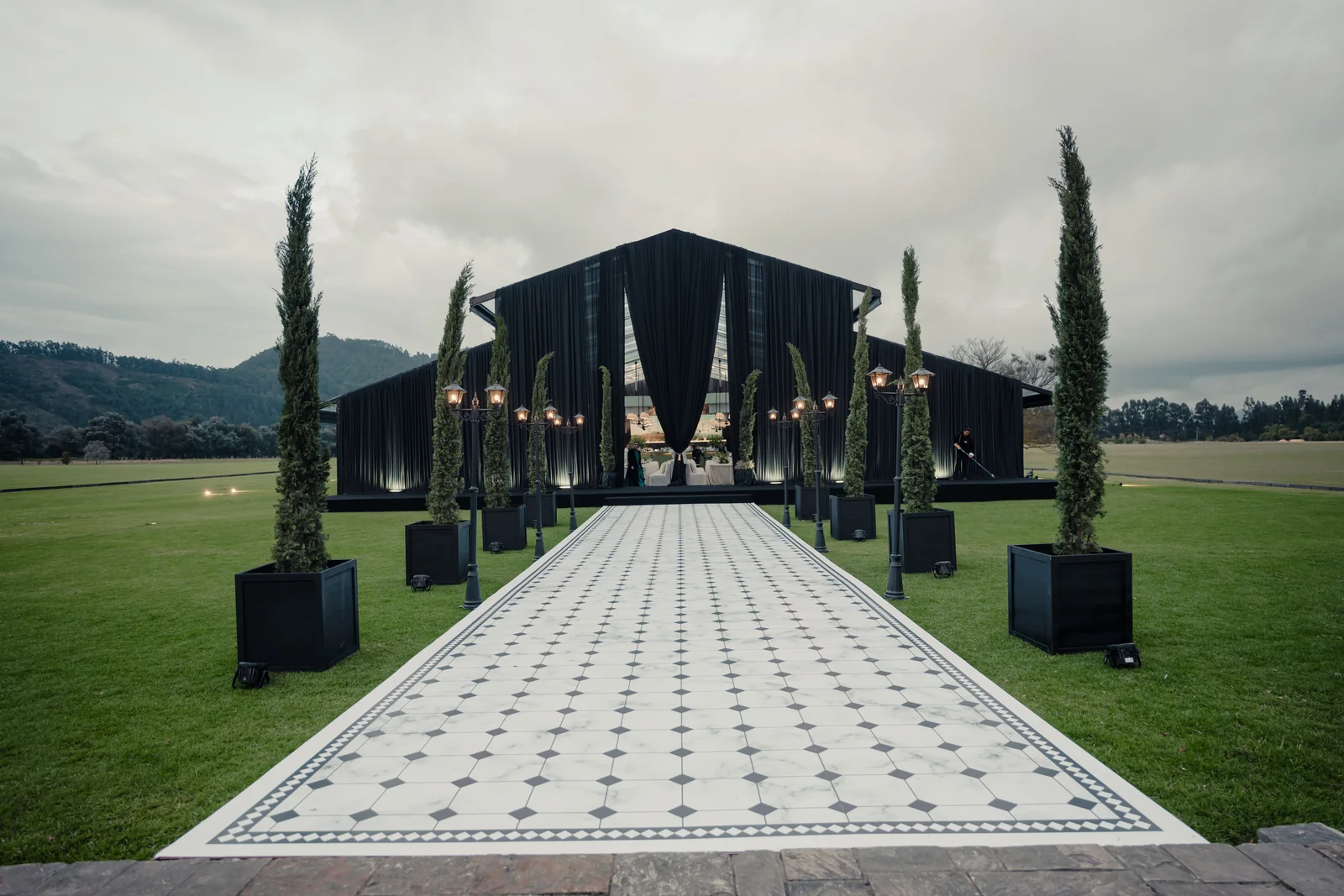 Black and white aisle framed by cypresses
